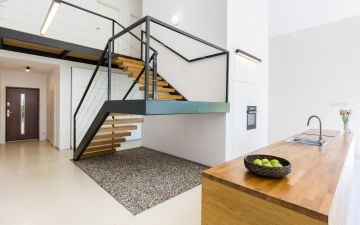 Modernistic interior with massive staircase of black metal and wood, and space filled with pebbles underneath